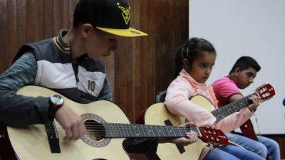 Crianças aprendem a tocar violão no projeto “Juventude em Ação”